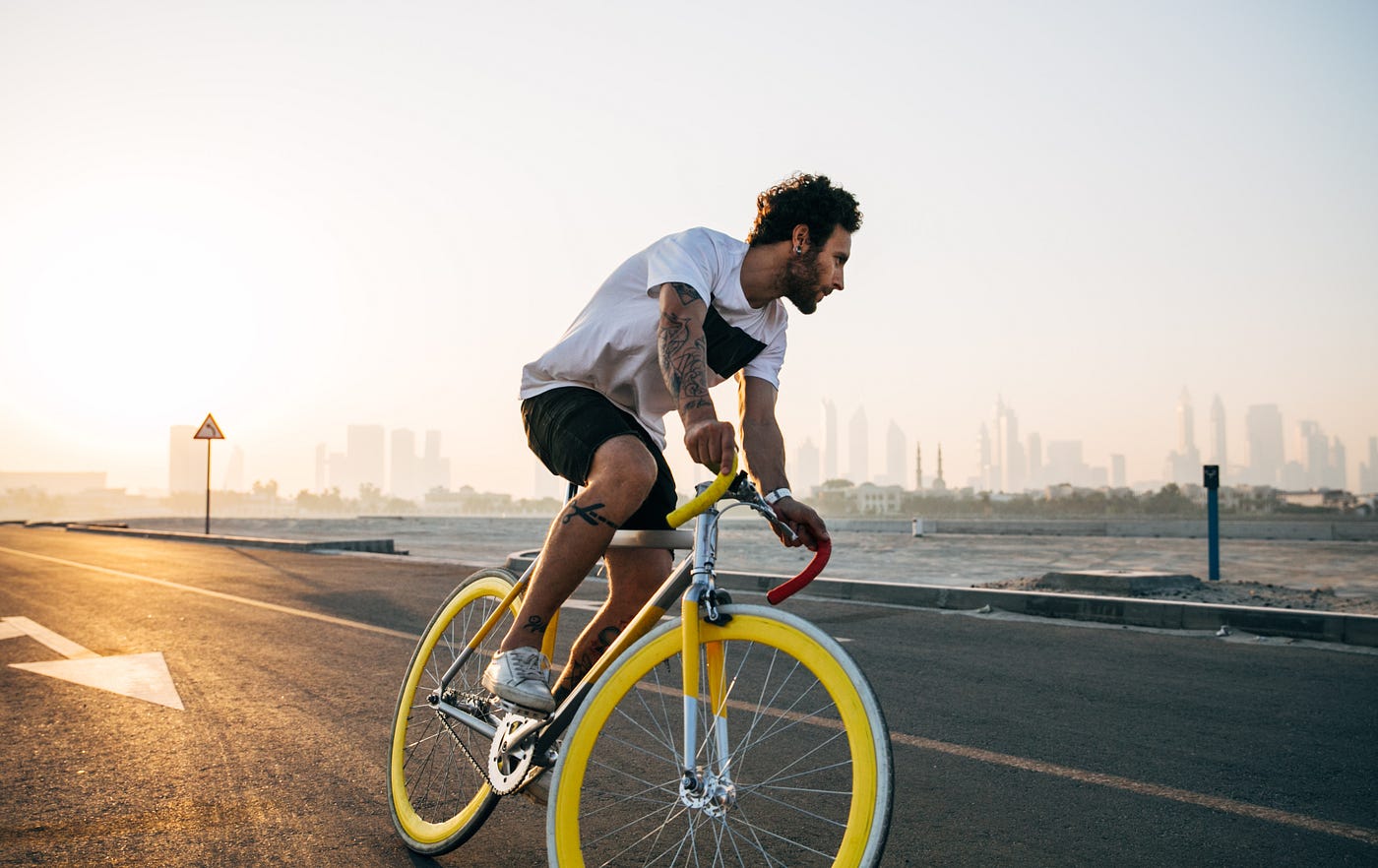 A man rides a rode bike with yellow-rimmed wheels. Cardio can also help to increase your metabolism, which is how your body burns calories at rest. A higher metabolism means you will burn more calories even when not exercising
