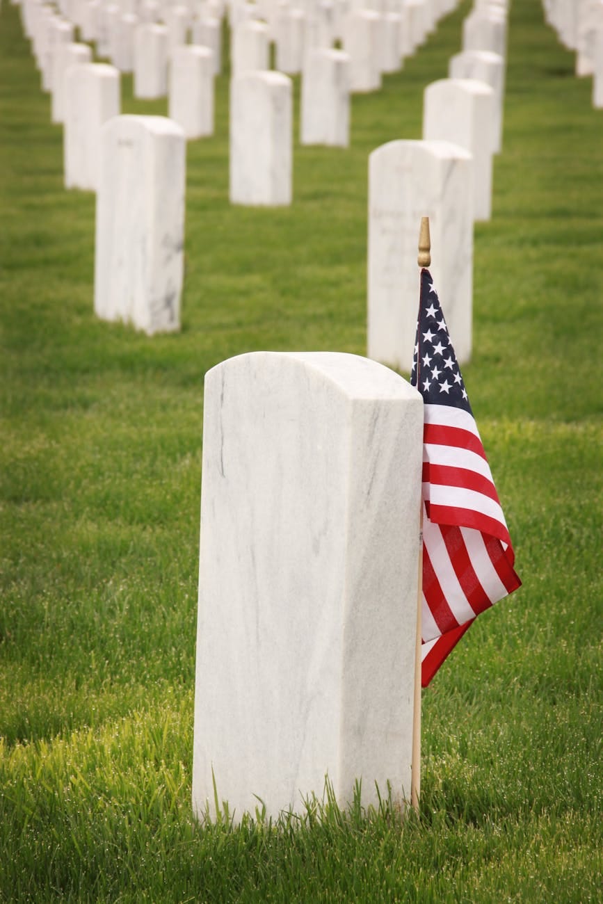 Mickey Markoff Air Sea Exec 2024 — Grey gravestone with American flag in green grass posted on mickey markoff article on the net worth of legacy and paying tribute to veterans