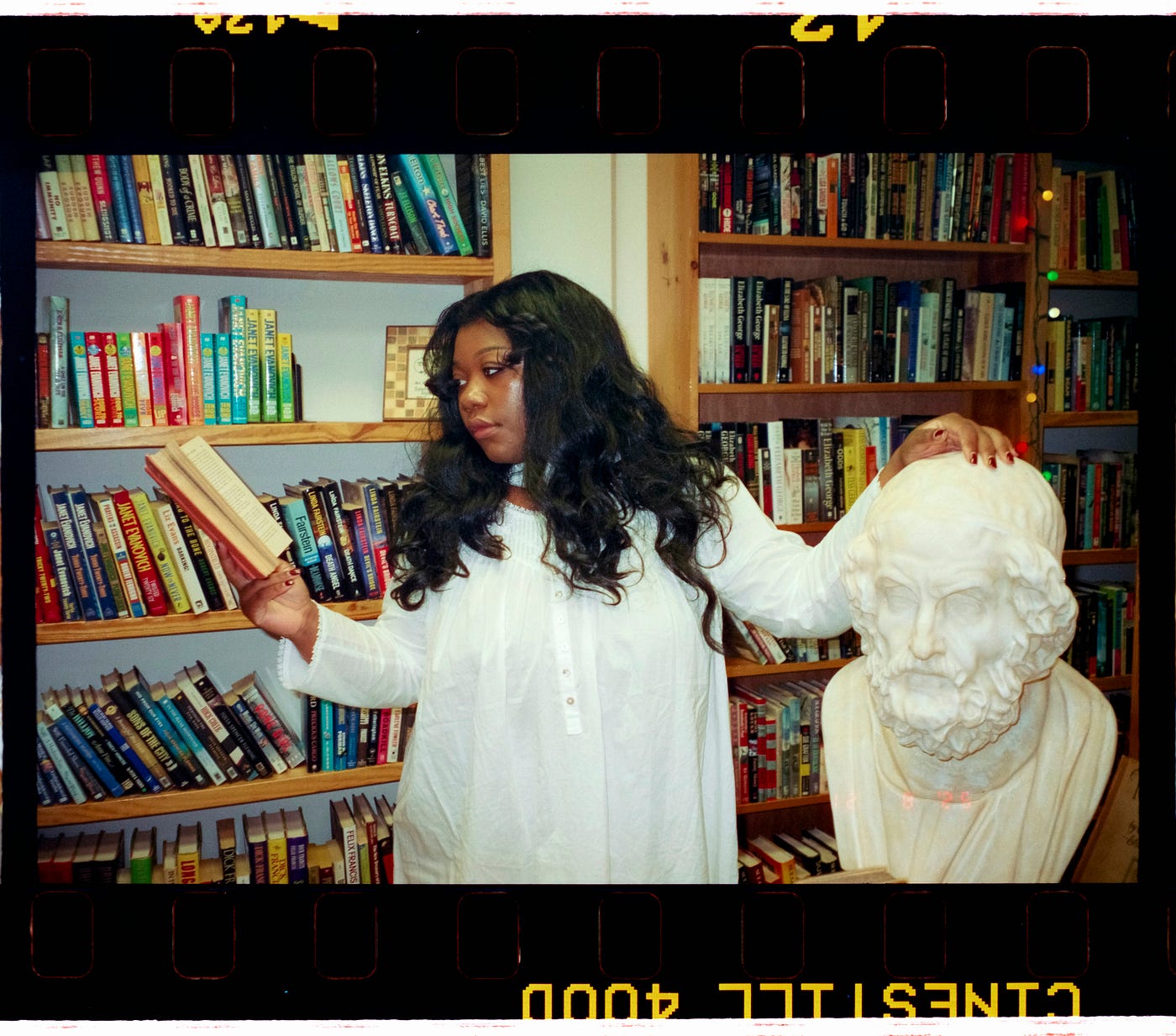 한 여성이 철학자 조각상의 머리를 만지며 책을 읽고 있다.<BR>