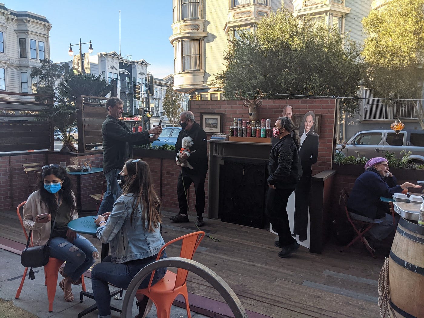 Patrons eating and talking on an outdoor deck with a fireplace and mantel outdoors in San Francisco.