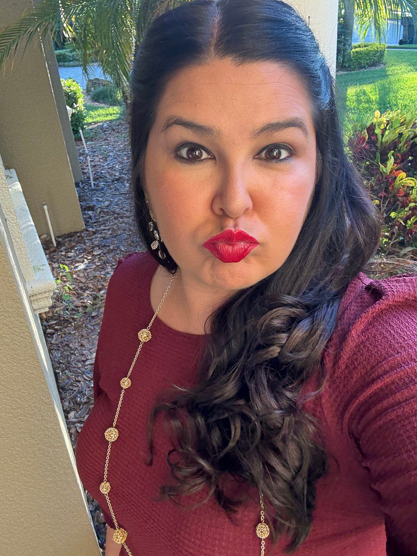 버건디색 드레스와 금 목걸이를 착용하고 키스하는 표정을 짓고 있는 작가의 셀카.