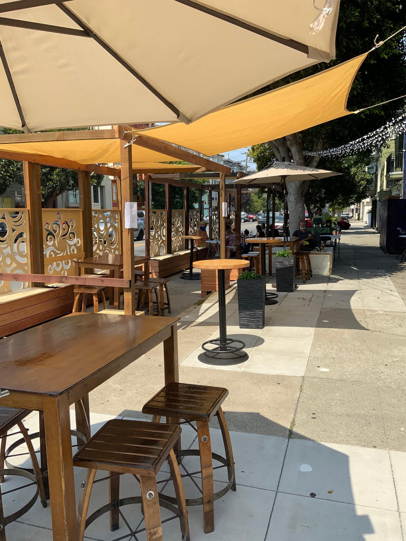 Outdoor dining area—wooden tables with a large umbrella above each.