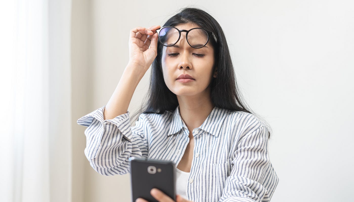 a round-faced woman wearing reading glasses on her forehead