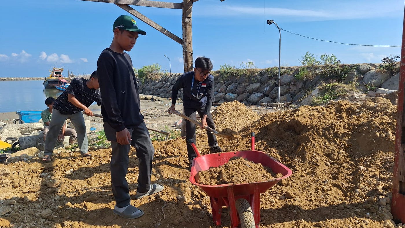‎Mahasiswa KKN PPM Kelompok 15 Unimal Gotong Royong Lakukan Penimbunan Pondasi PPI di Desa Tanoh…