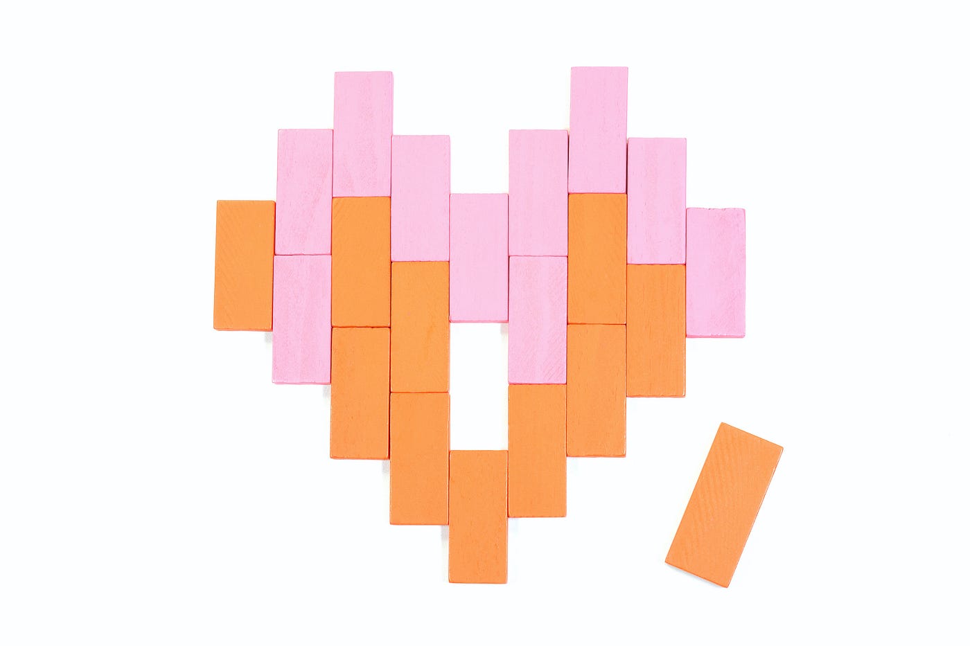 Orange and pink rectangular blocks arranged in the shape of a heart with one piece missing (an orange one next to the heart)