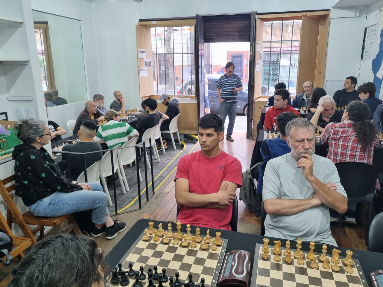 Un hombre jugando una partida de ajedrez con un reloj en la pared.