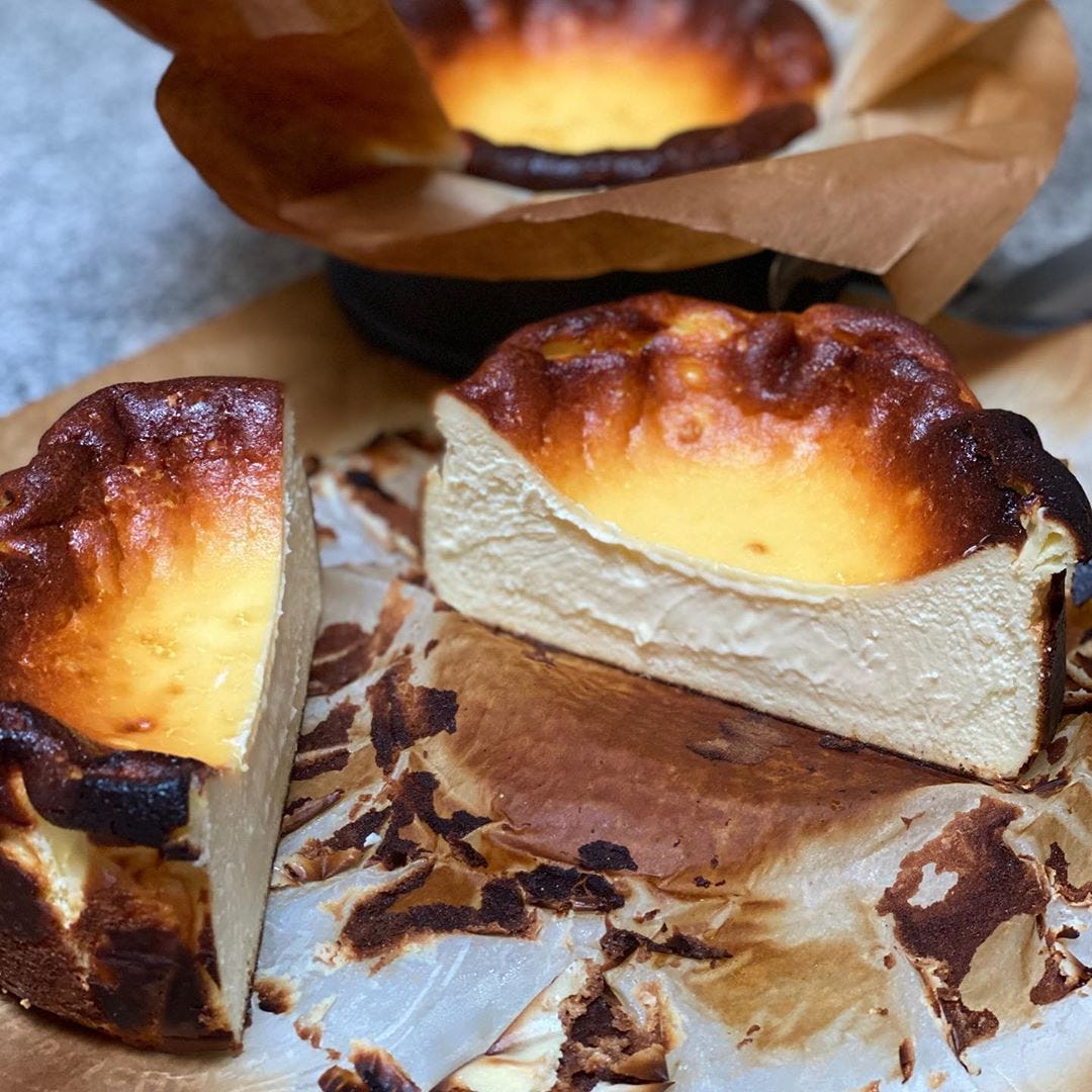 A halved basque cheesecake in a small custard tin,