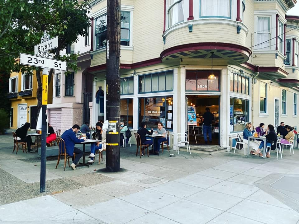 The Spice Jar’s corner location. People are dining at small tables on the sidewalk.
