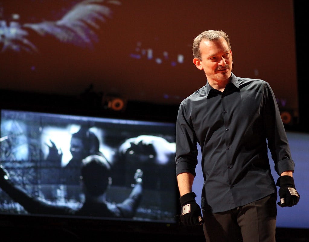 A man dresed in black with special gloves on demonstrates how the movement tracking technology was generated for the movie Minority Report.