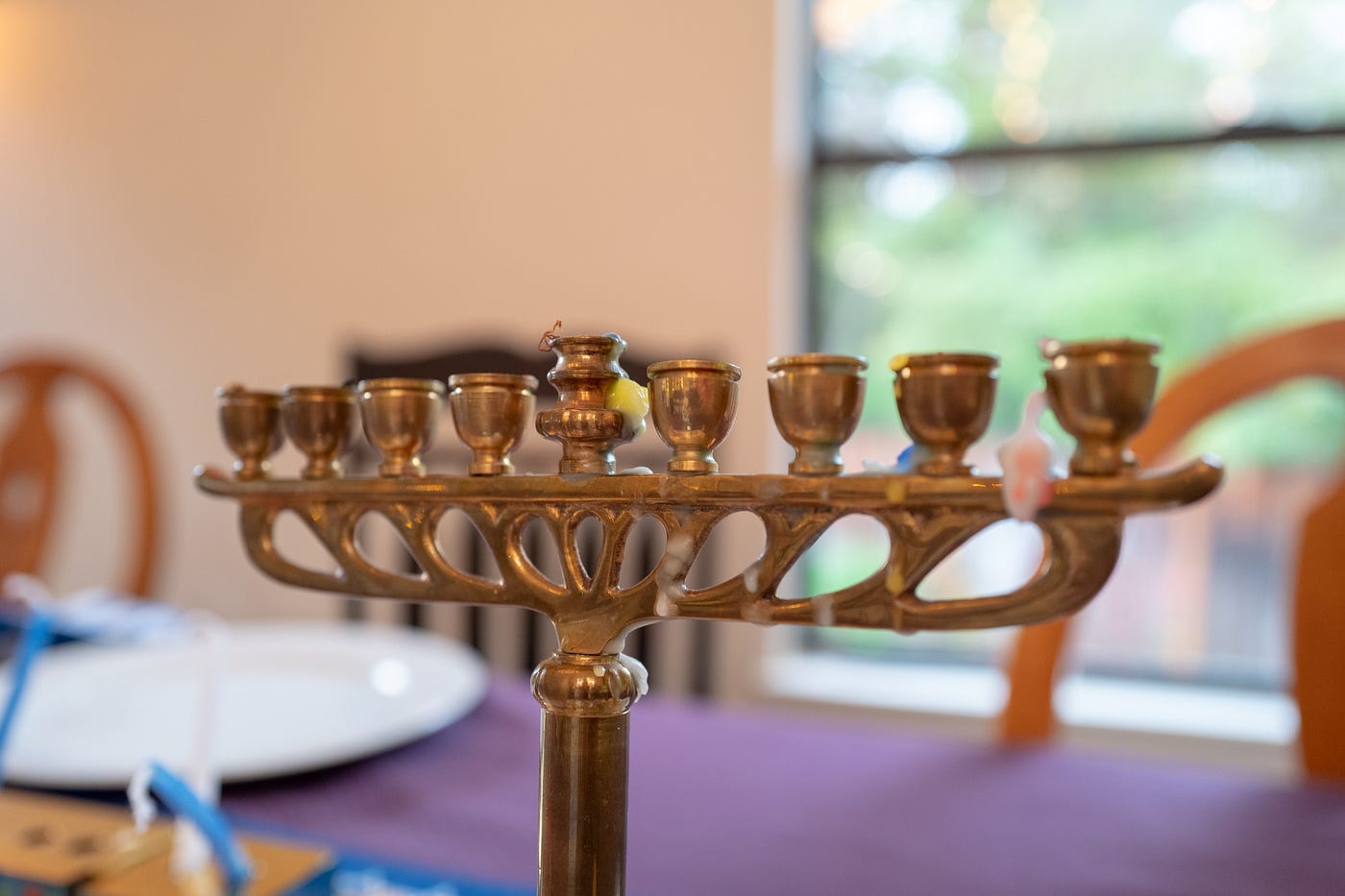 Closeup on a menorah with no candles in it on a dining table during the day.