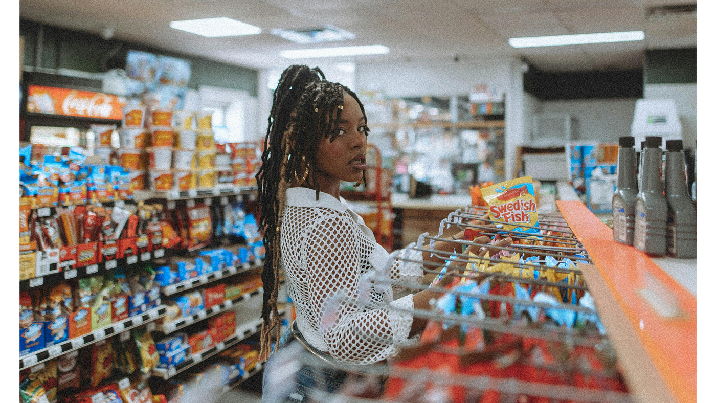 AA woman in aisle, picking snacks | Photo by Nina Hill via Pexels