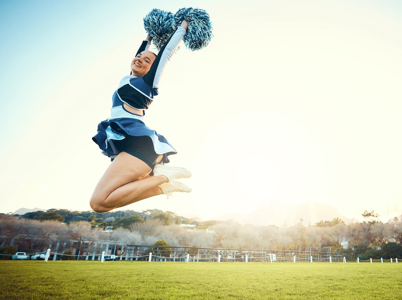 “ Cheerleader, woman jump to sky for sports performance or celebration with energy outdoor. Cheerleading person dance in nature with space for training, exercise and sport competition to celebrate goal ” | by PeopleImages | Shutterstock