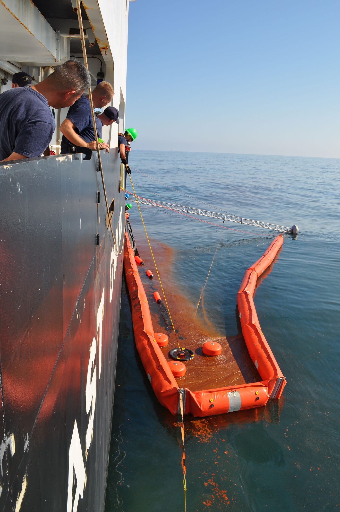 Oil recovery during the Deepwater Horizon response. The orange floating barrier is the boom. Its job is to concentrate the oil into a smaller area, where a skimmer can collect it more efficiently. Public domain