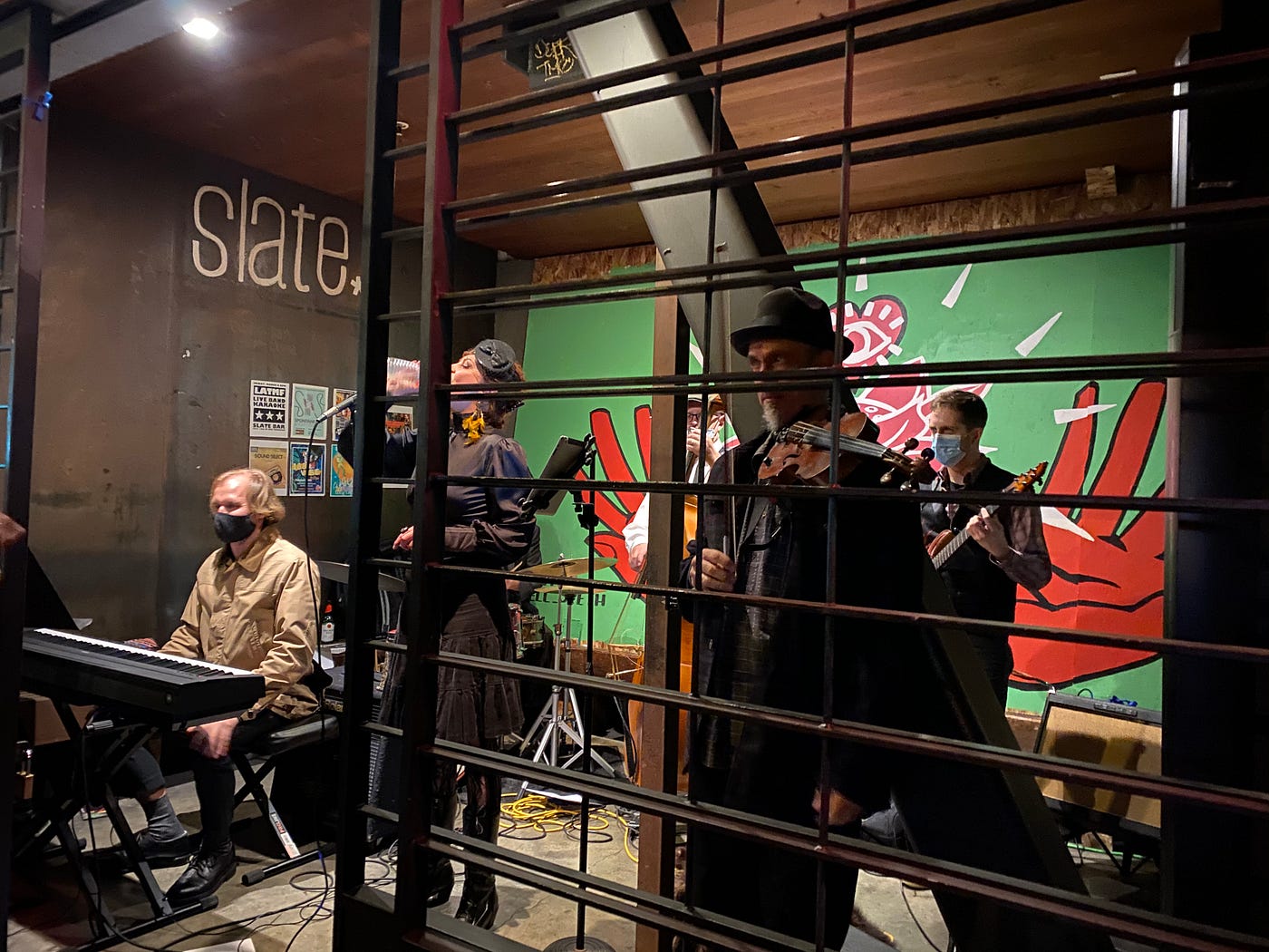 A band performing in a small enclave with a mural on its back wall.