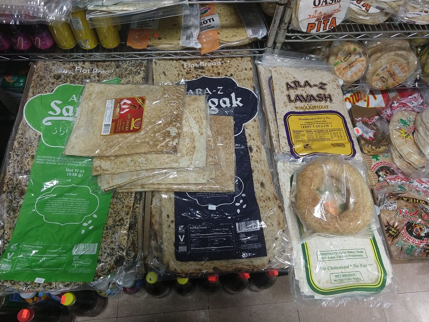 Rectangular clear packages of lavash on a shelf in a store next to shelves stocked with pita.