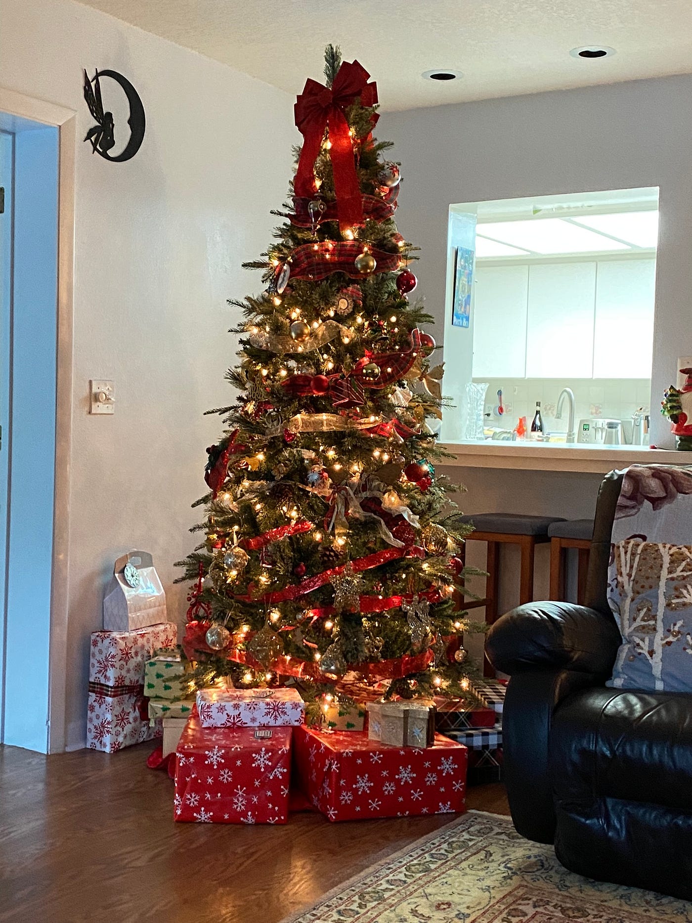 Christmas tree fully decorated with wrapped gifts under it.
