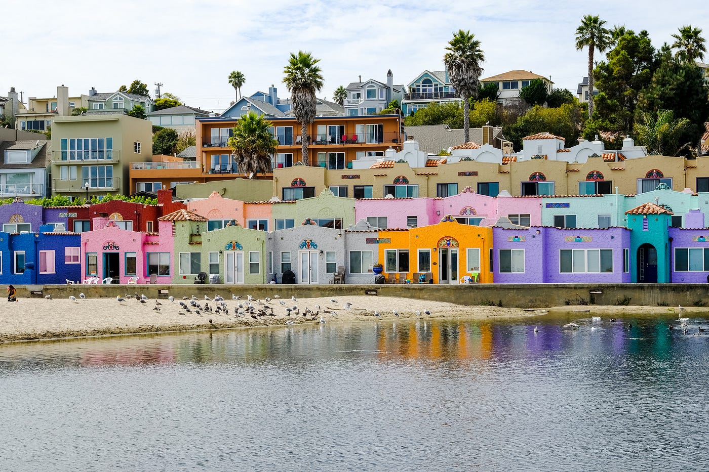 A row of multicolored pastel houses on a beach during the day.
