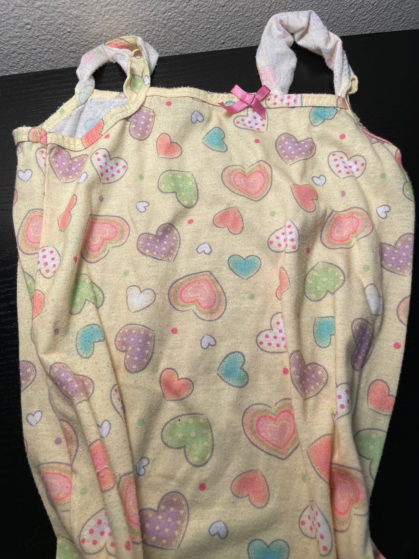 A child’s yellow nightgown with pastel hearts on it.
