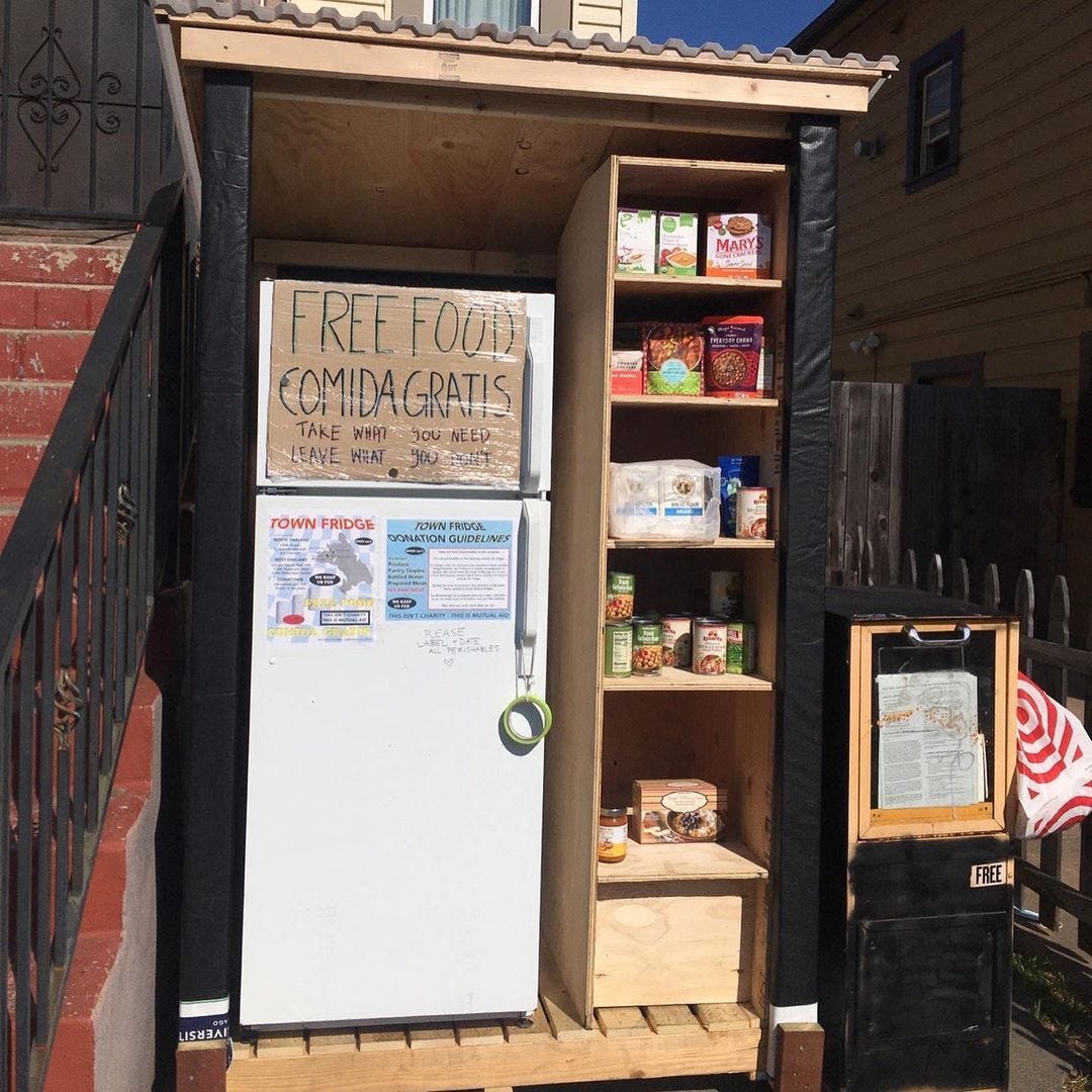 A refridgerator outside with a sign that says “Free food / Comida gratis.”