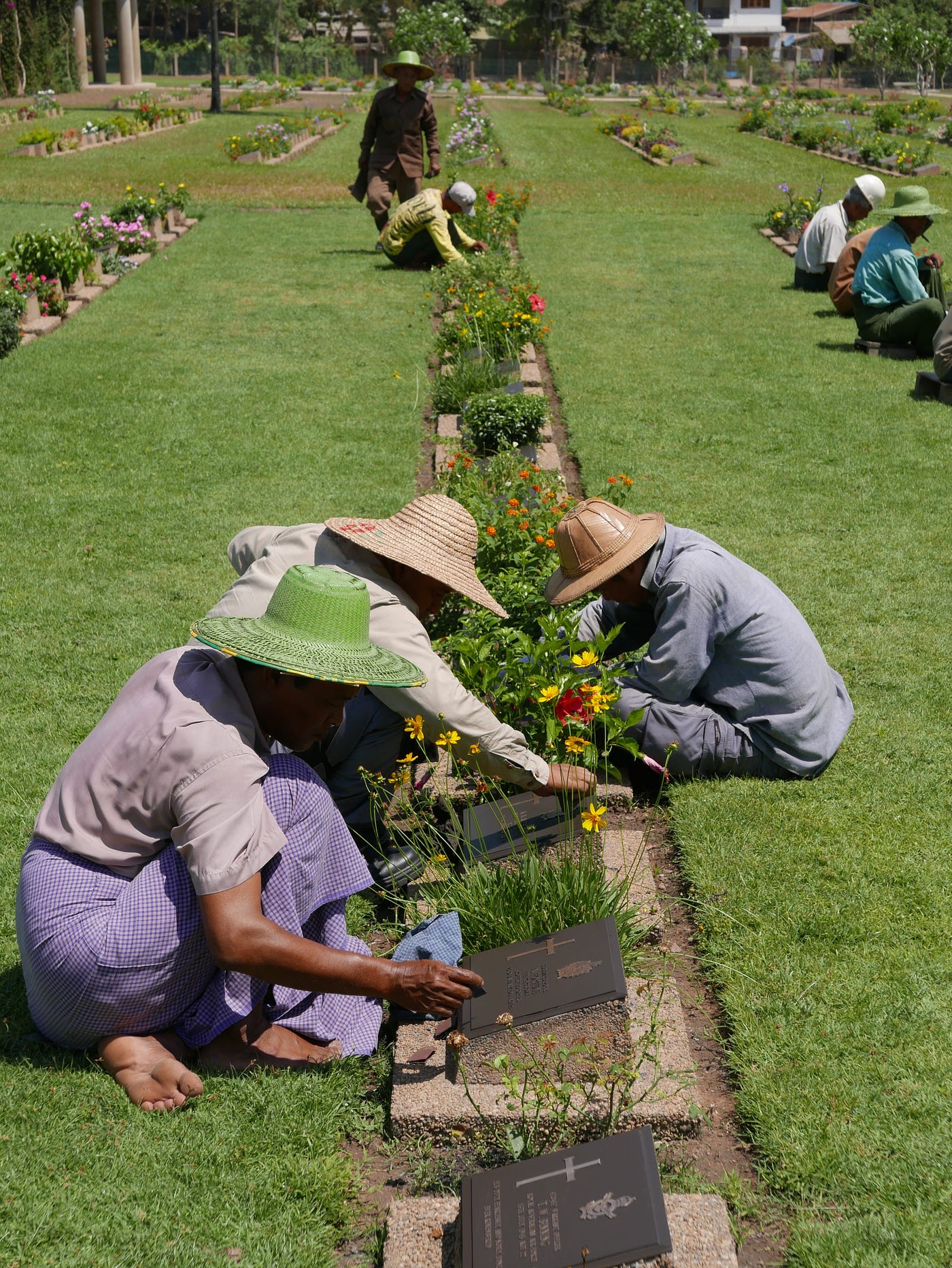Photo by Author — cleaning grave markers — the Taukkyan War Cemetery, Yangon (Rangoon), Myanmar (Burma)