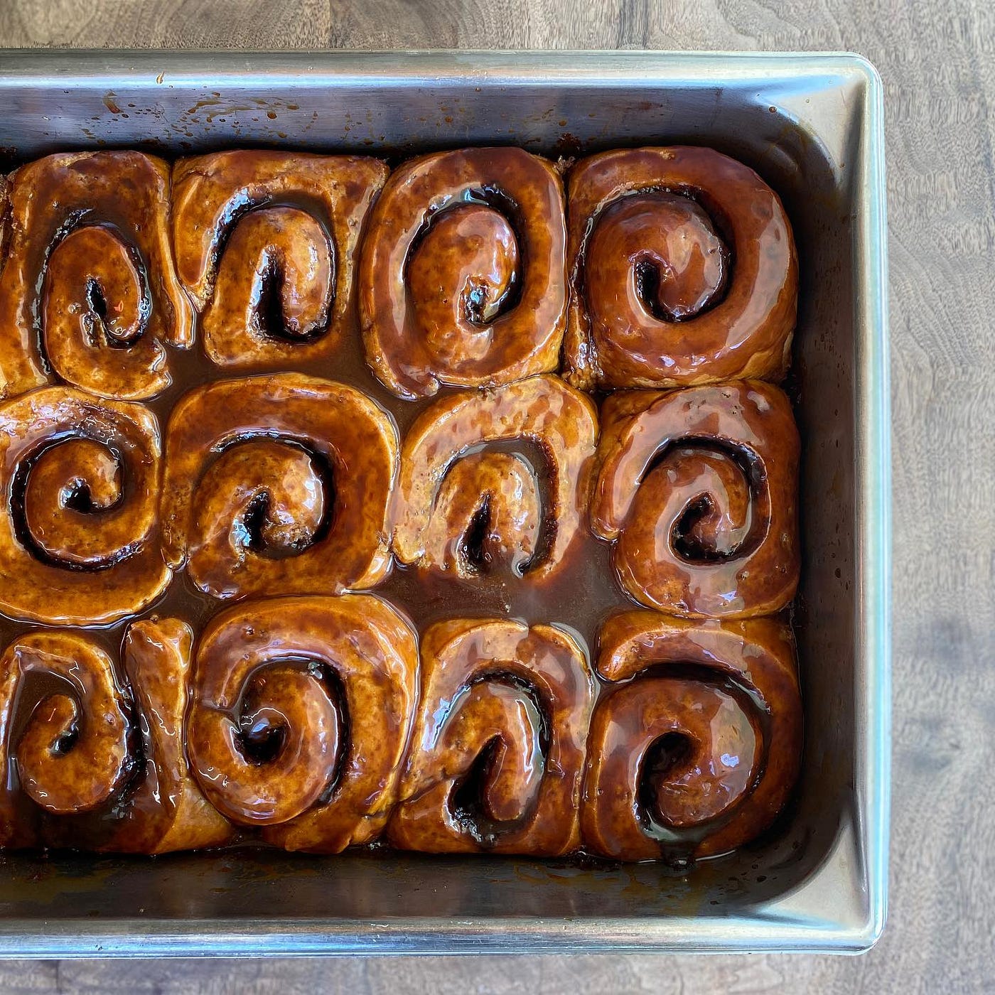 A tray of cinnamon rolls smothered in dark-brown glaze.