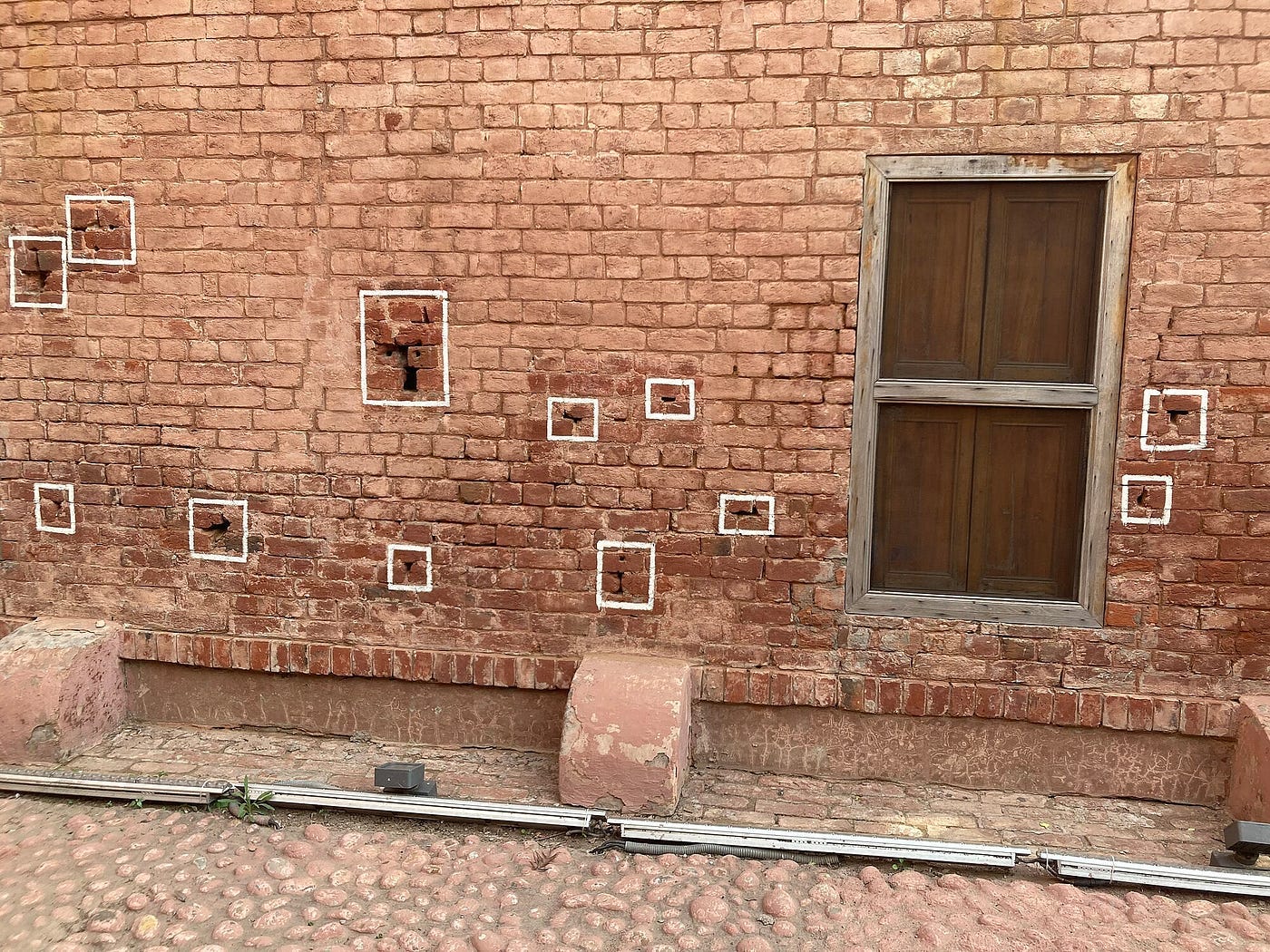 Preserved bullet indentations on the original brick walls of the Bagh, marking the height and trajectory of the 1,650 rounds fired. Via Wikimedia Commons (CC BY-SA 4.0)
