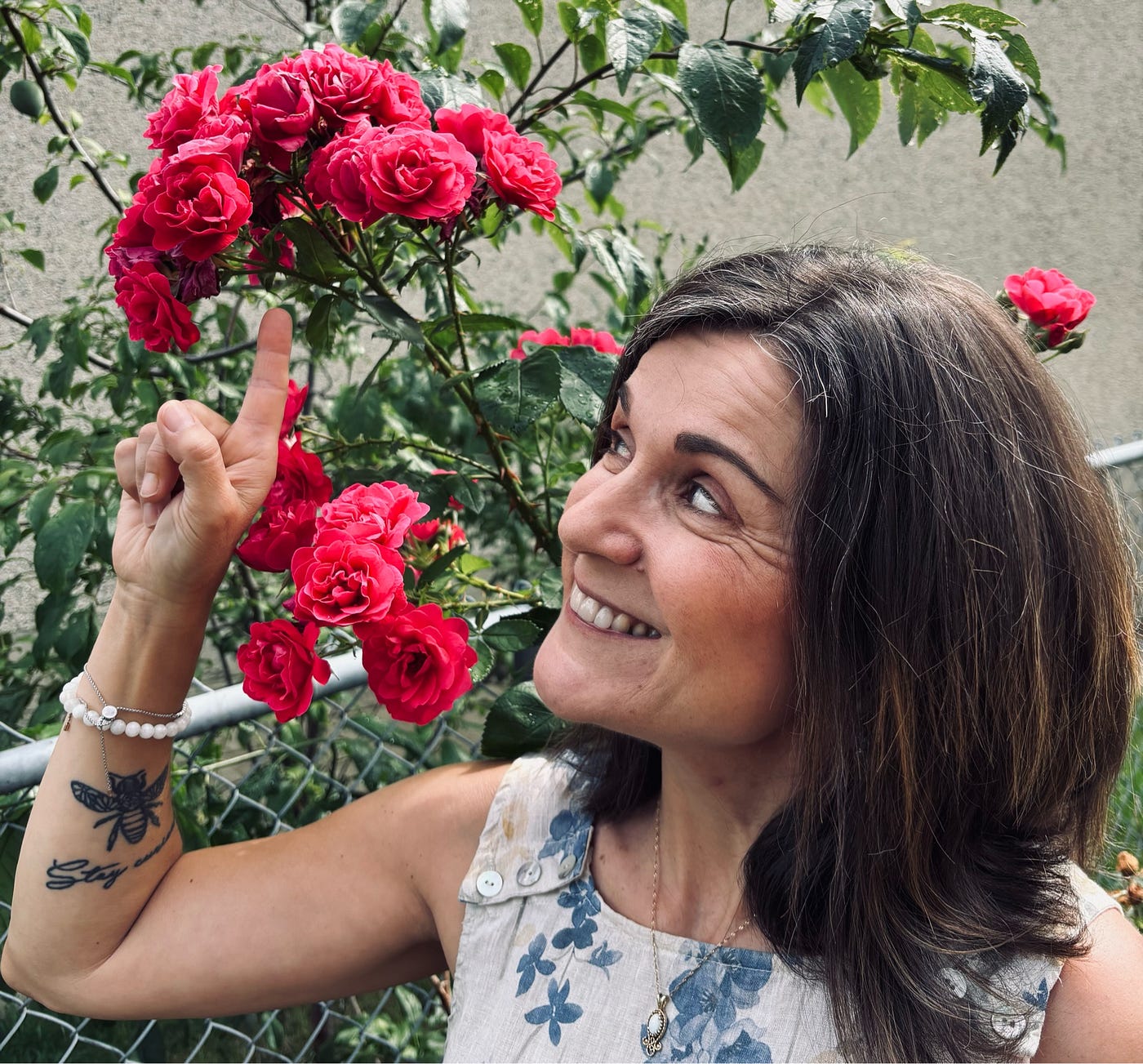 분홍색 장미꽃이 모여 있는 곳을 손가락으로 가리키고 있는 여성.