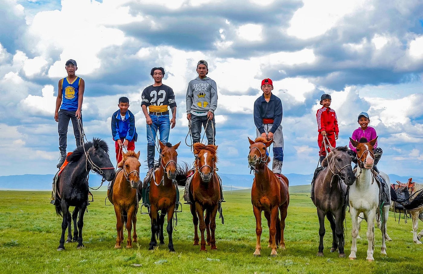 Mongolian child riding horse across open steppe