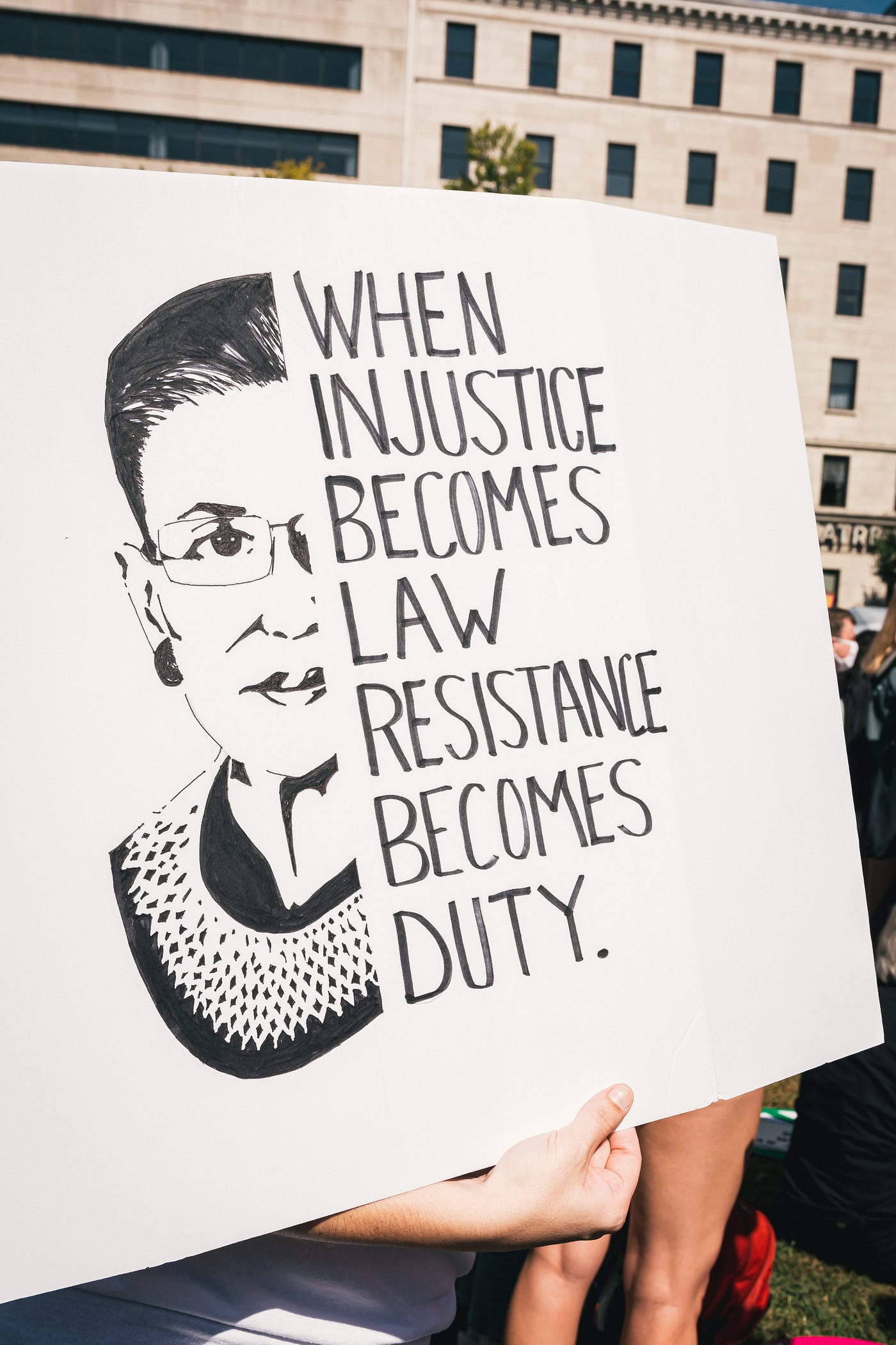 A protest sign says When Injustice Becomes Law Resistance Becomes Duty
