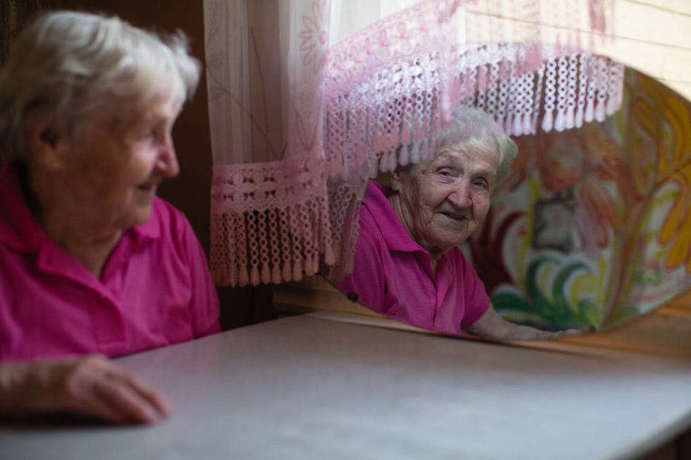 거울에 비친 행복하고 만족스러운 노부인의 모습.