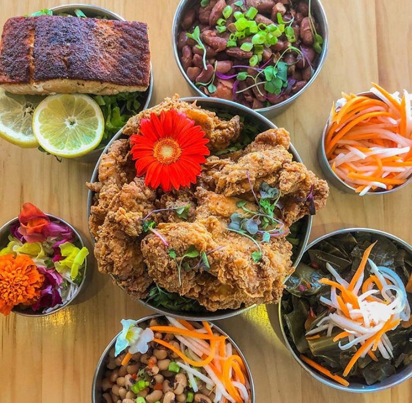 Overhead view of a variety of Creole dishes servied in metal bowls on a wooden tabletop.