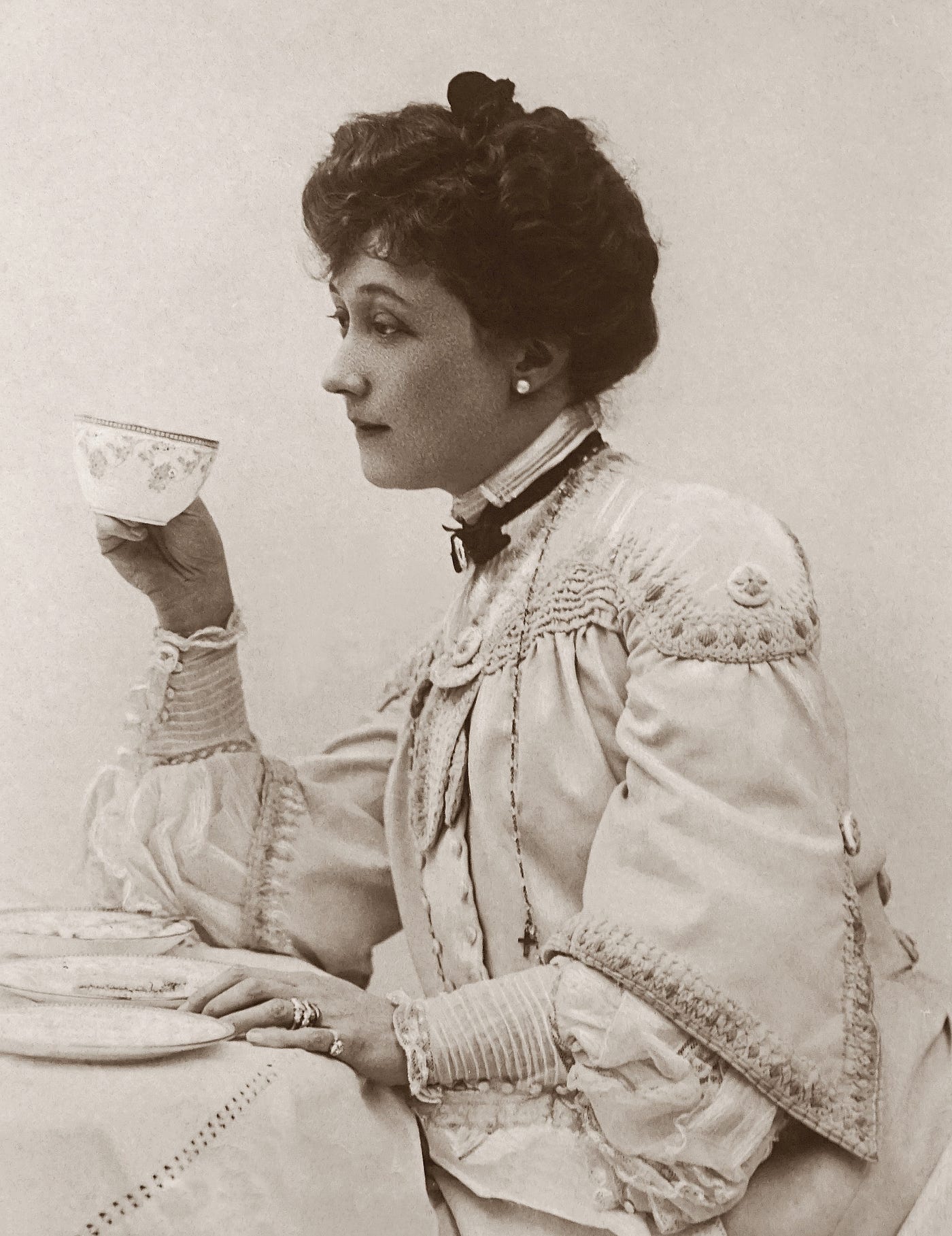 Classic black and white portrait of a Victorian woman drinking tea.