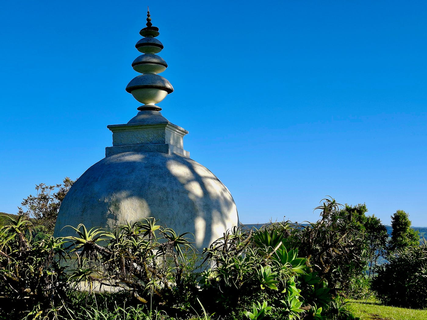 The stupa is set back from the scenic view of rolling hills that recede like waves.