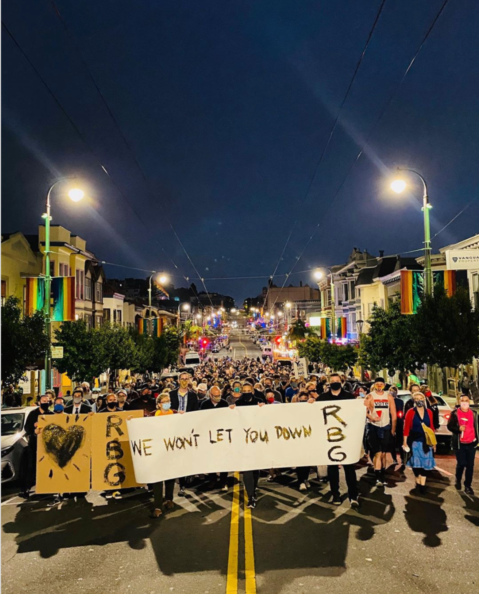 A wider shot of the crowd with the “We won’t let you down” banner marching in the Castro at night.