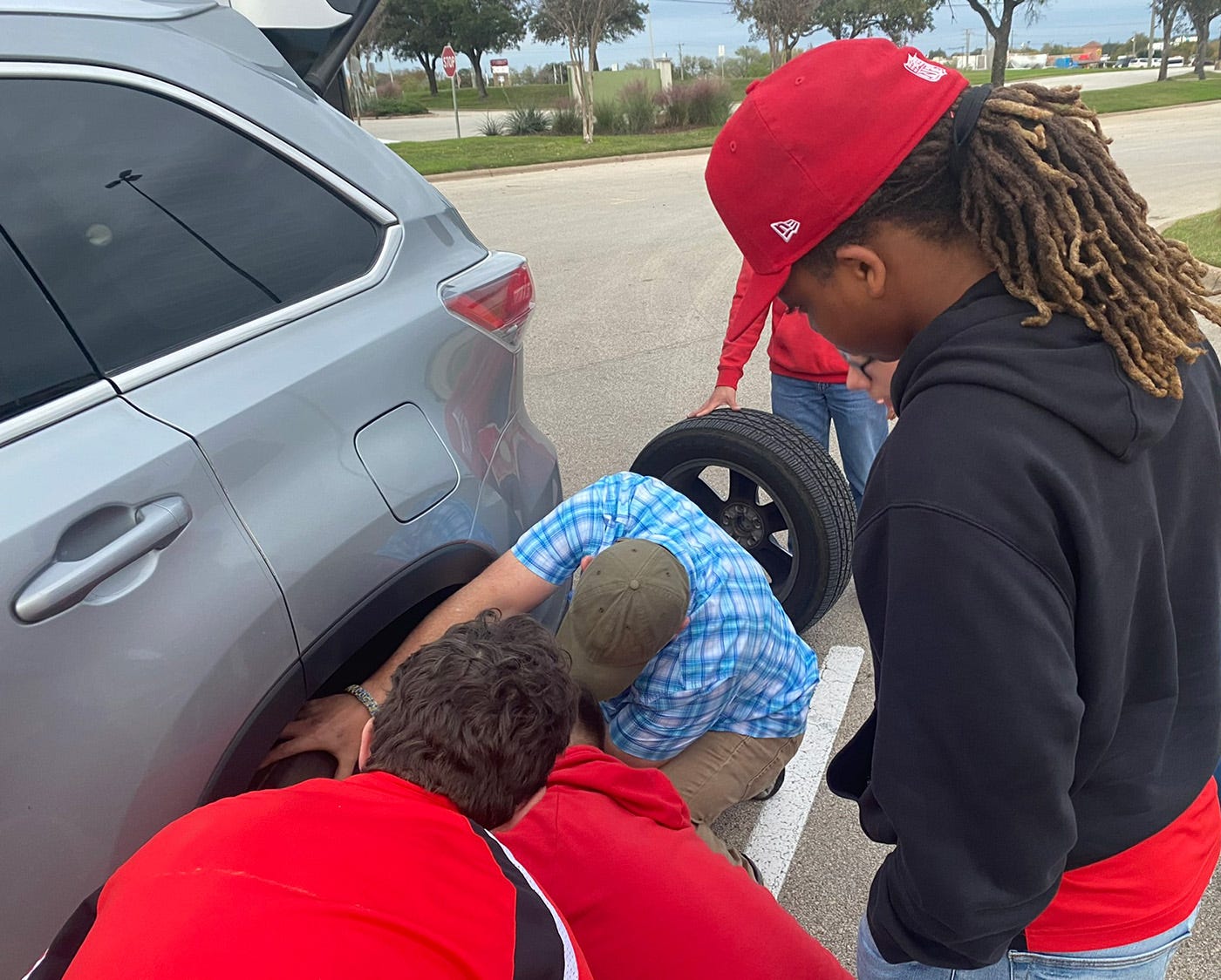 Photo showing teens changing a tire