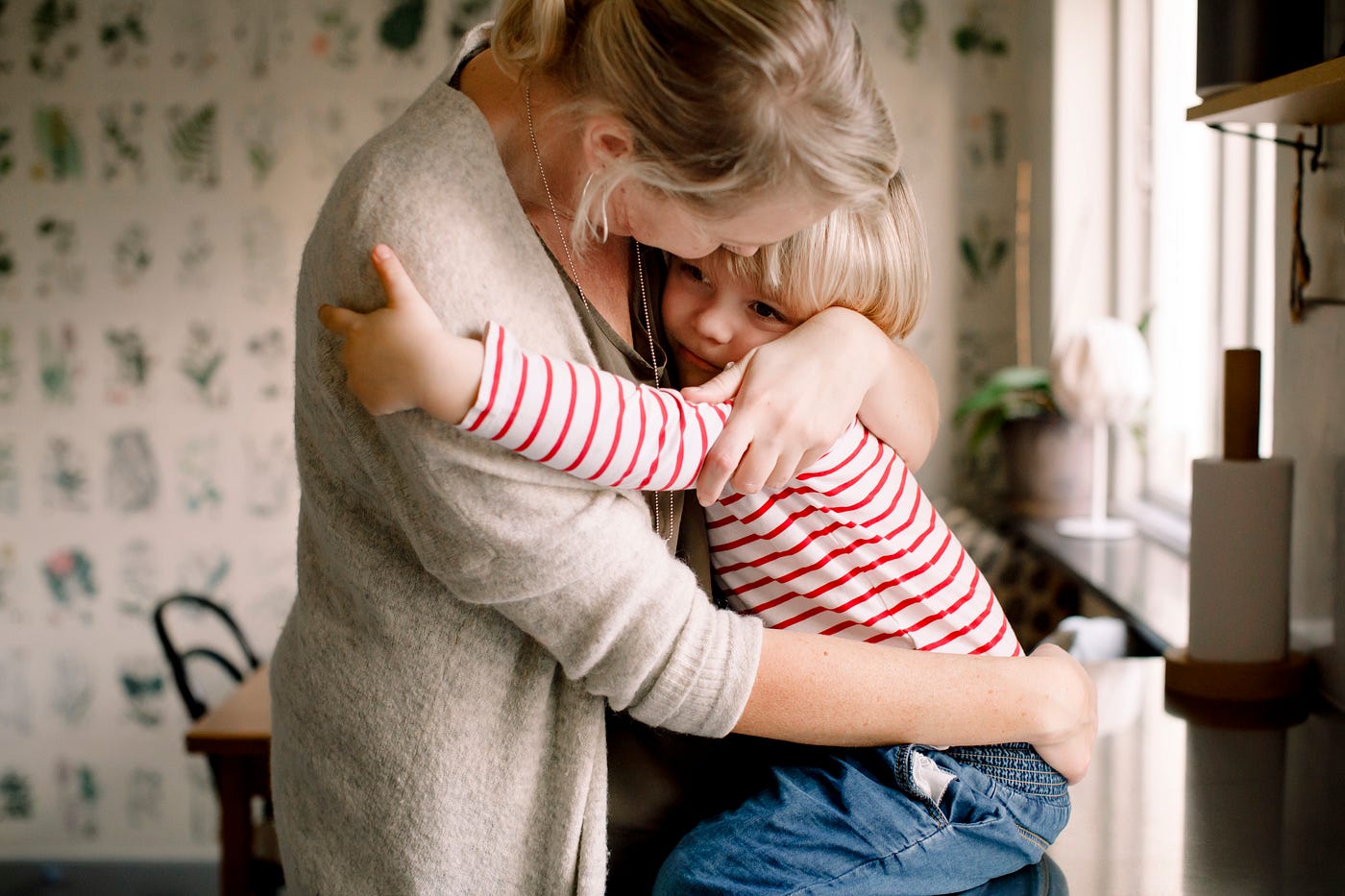 A photo of a mother holding her child in their kitchen.