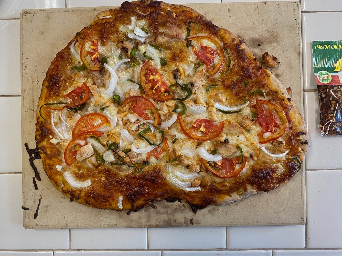 Toppings added — The final shape is out of wack as I was trying to fit it onto the pizza stone — Photo by Author