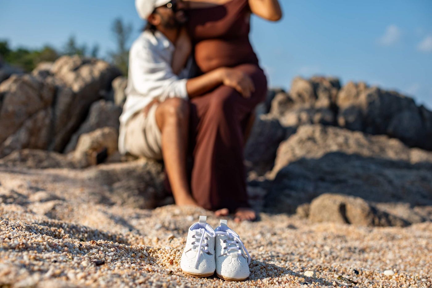 Expecting couple holding hands and an ultrasound photo on a Koh Samui beach.