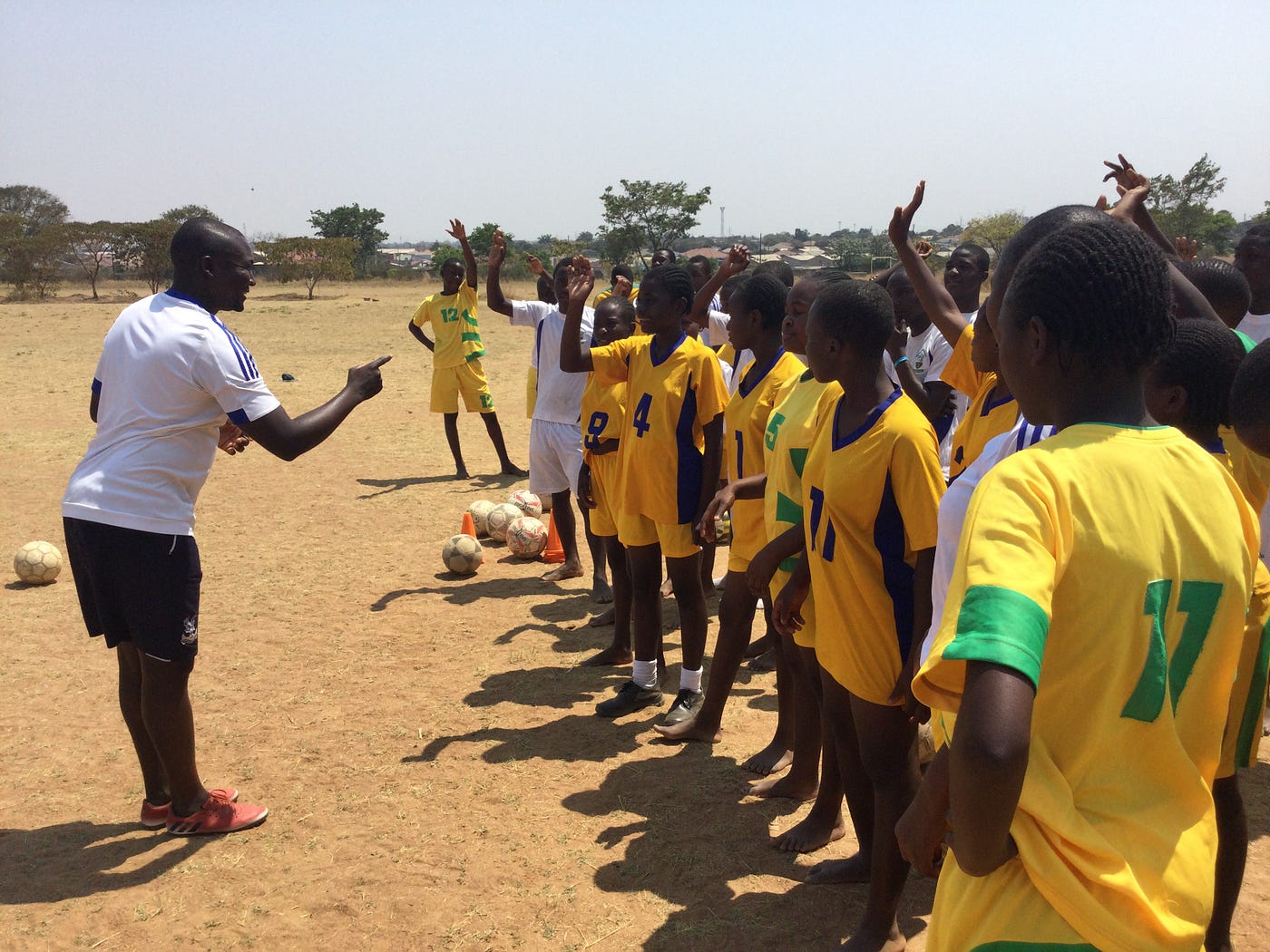 Ashoka Fellow Elvis Nshimba talking to a group of sports players in yellow jerseys.