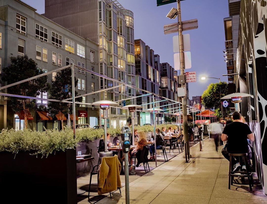 A view of socially distanced tables on a terrace in a city street.