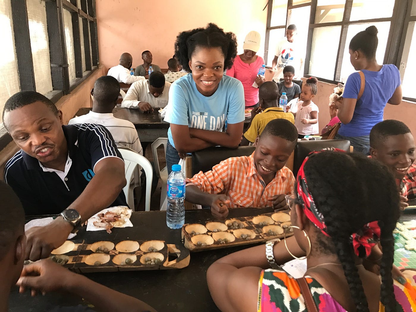 Bambo Oguntayo (far left) and Bisola Daramola (center), members and volunteers at the Games for a Cause initiative, with children playing the Ayo Game.