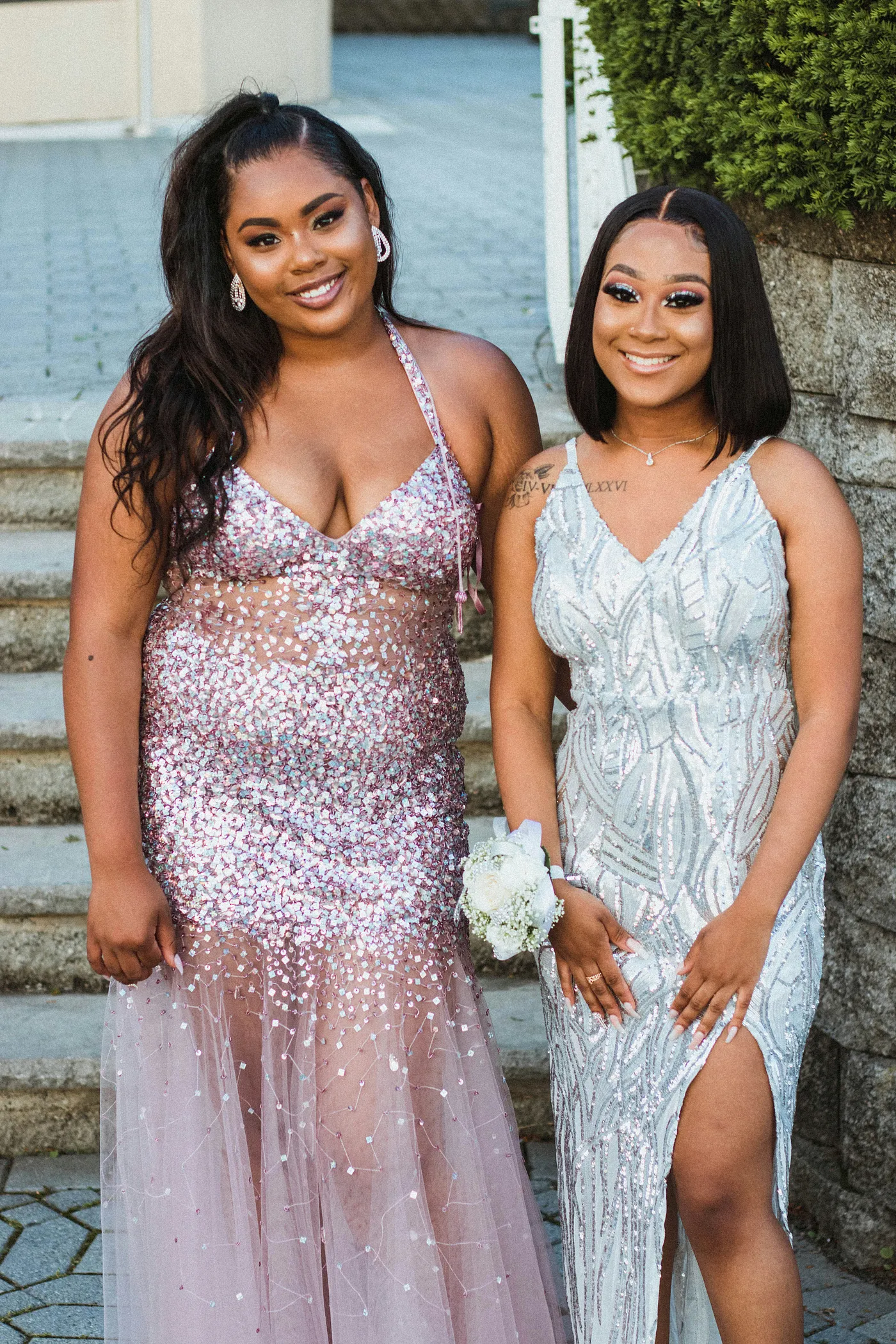 Two girls standing side by side wearing sparkly prom dresses