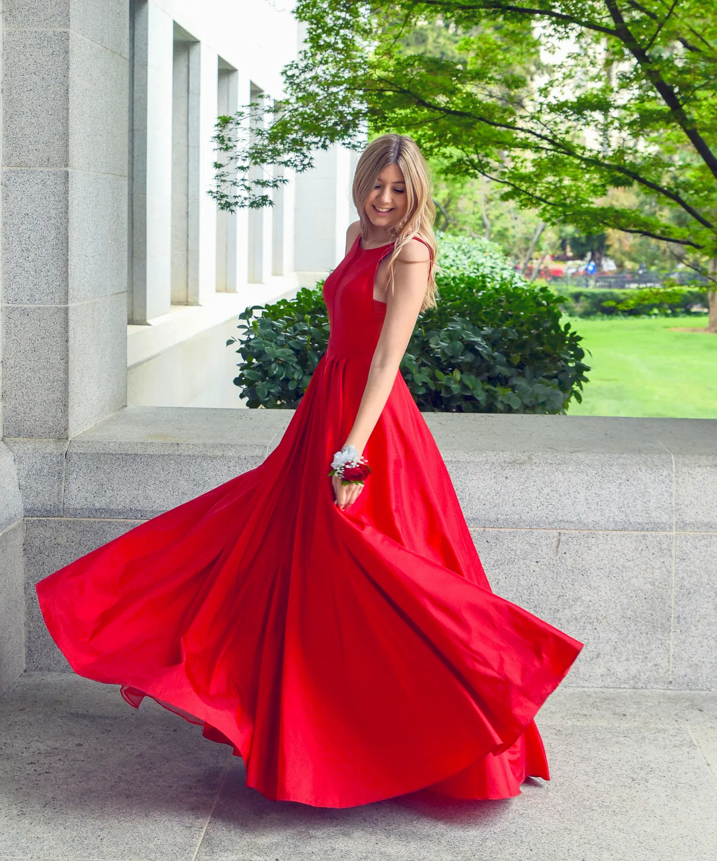 A girl wearing a long red prom dress