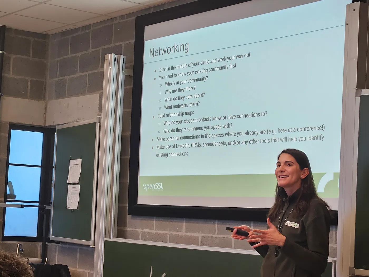 Image shows a speaker, Amy Parker, in front of a well-lit classroom, presenting on "Three Keys to Successful Fundraising." Amy is a white woman with dark hair, wearing an OpenSSL sweater and a bright smile. The slide projected behind her is titled "Networking" and shares on the importance of building connections and relationships.