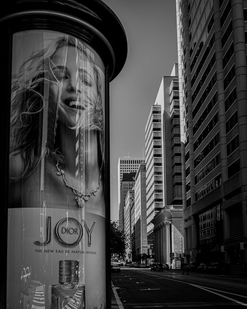 Black-and-white photo of an ad for Dior’s Joy fragrance on a city street.