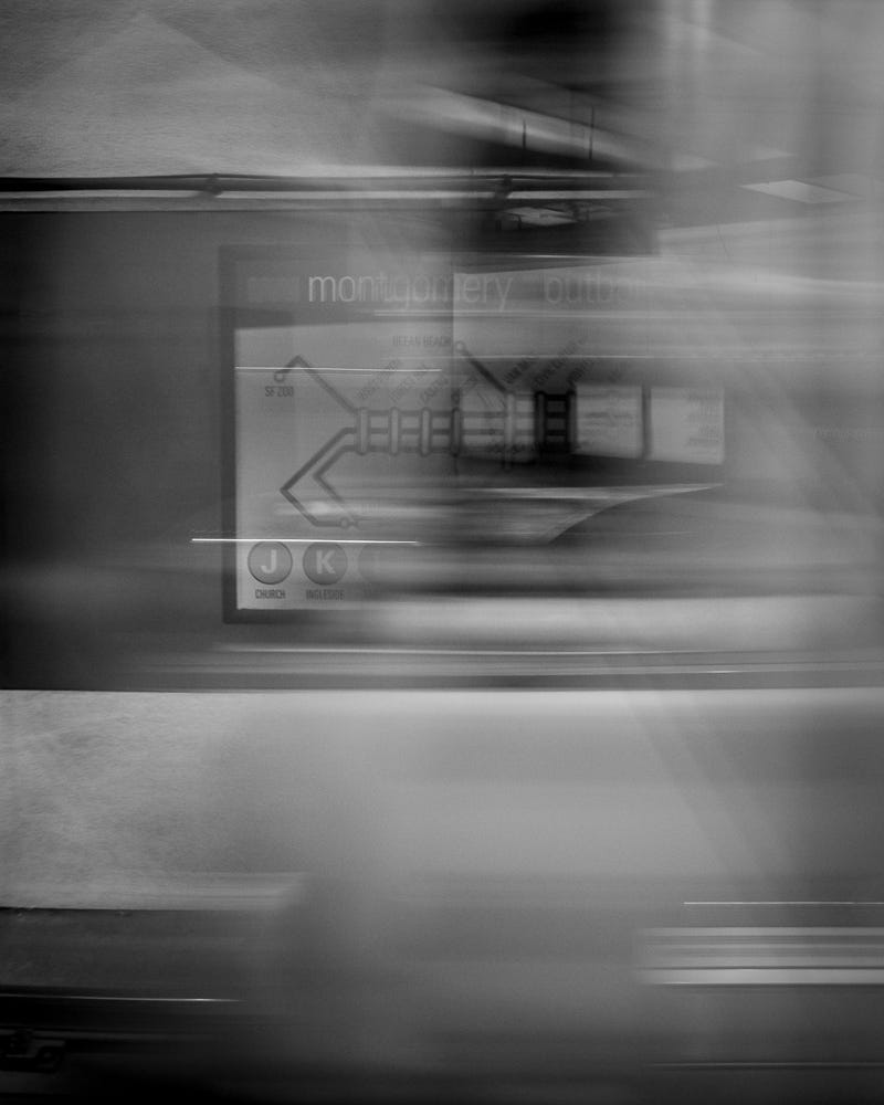 Blurred black-and-white photo of a train rushing in front of a sign for the Montgomery station.
