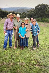 A family poses with rolling hills and trees in the background.