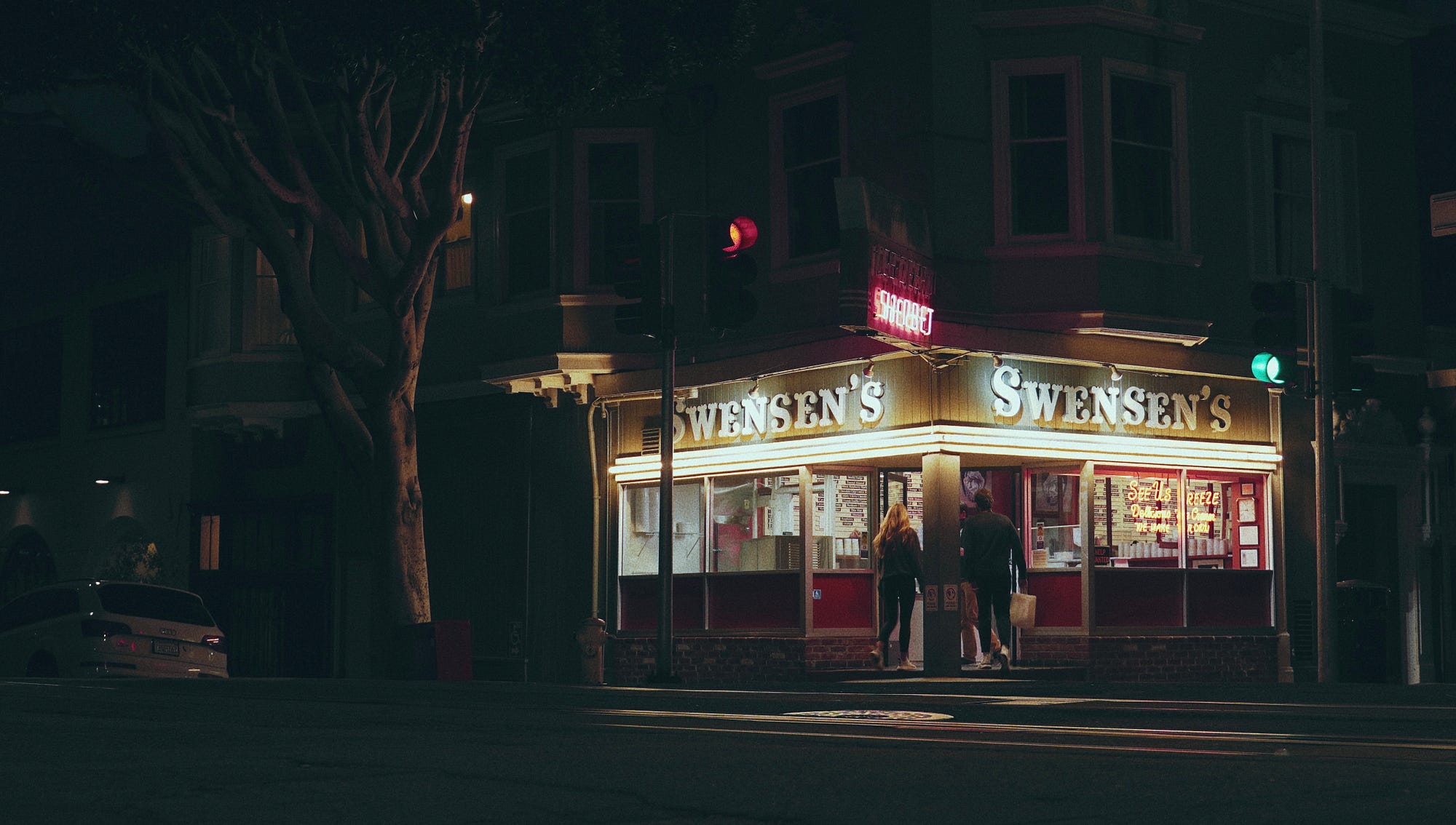 The exterior of Swensen’s at night, its signs lit up.