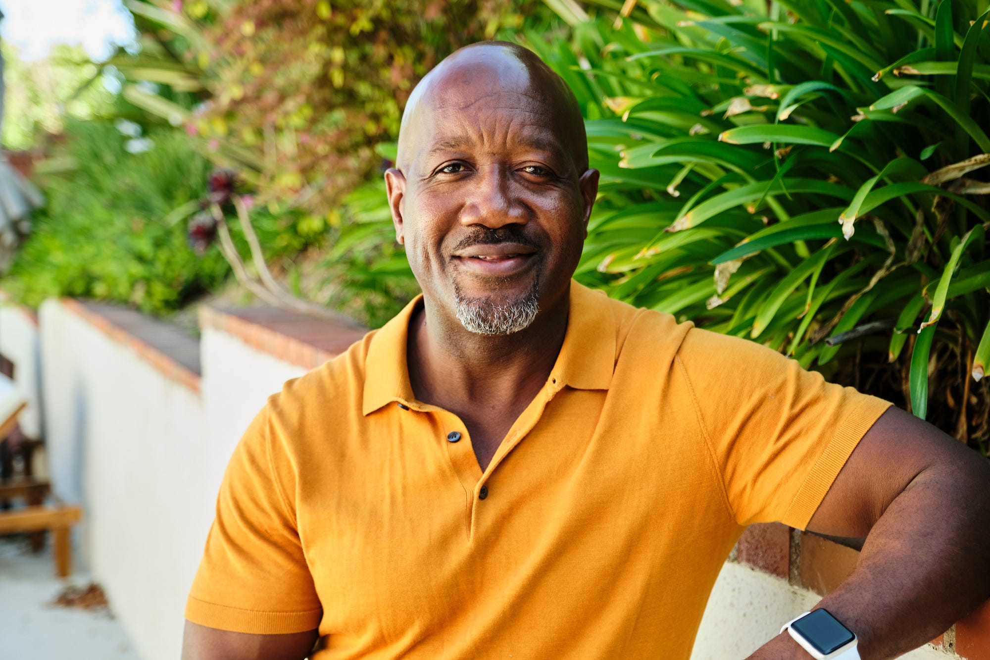 화창한 여름날 캘리포니아주 로스앤젤레스의 집 뒷마당에 서 있는 행복한 중년 남성.