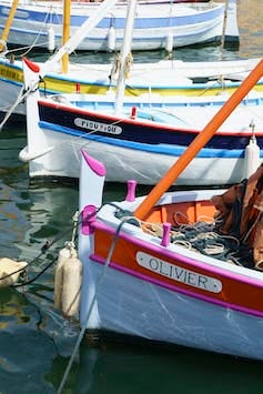 A row of boats, including one with a name plate calling it “Olivier” and the one behind it Pioupiou